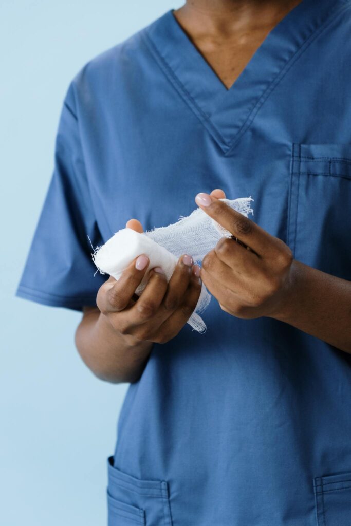 Close-up of a healthcare worker in scrubs holding a sterile bandage.